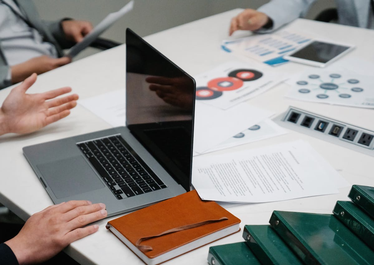Business compliance documents and reports arranged beside a laptop